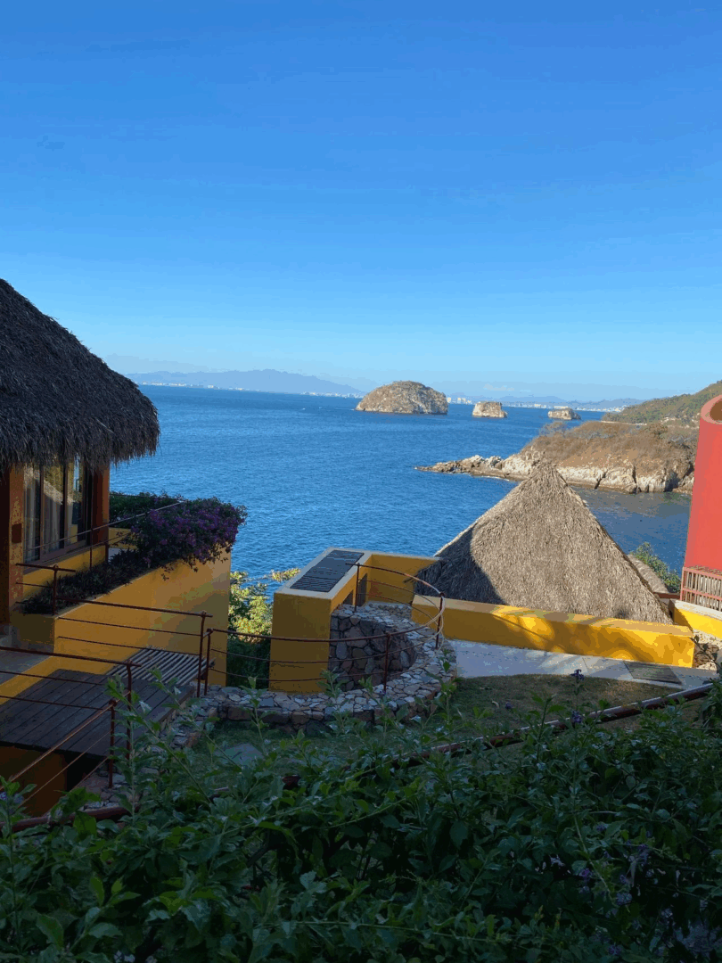 Coastal view with huts and rocky islands.