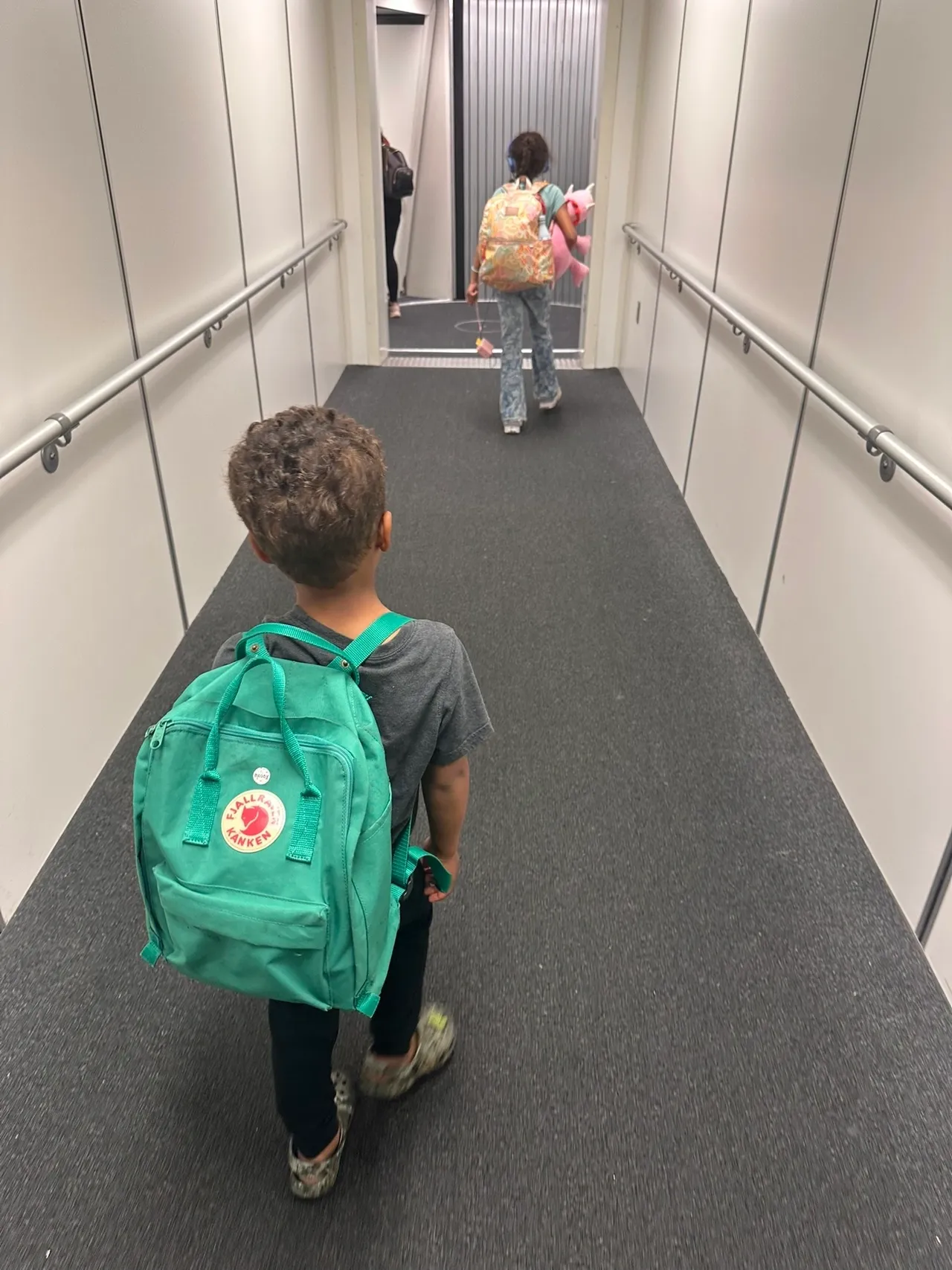 Children walking down an airplane jet bridge.