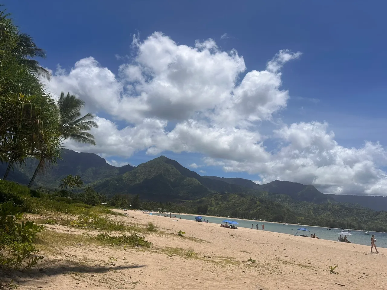 Tropical beach with mountains and cloudy sky.