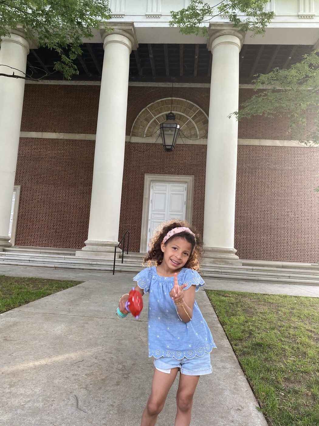 A young girl flashing a peace sign in front of the columned facade of Agnes Scott College in Decatur, Georgia