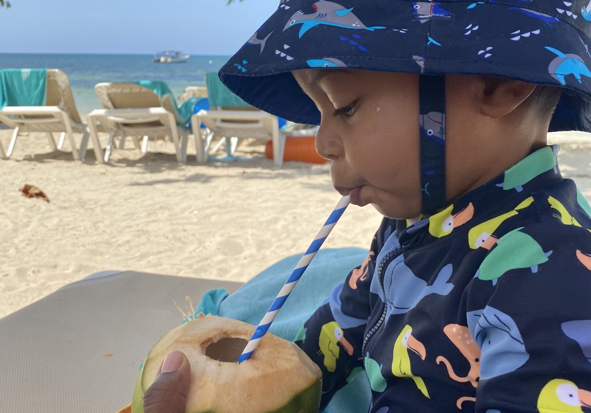 Young boy drinking fresh coconut water on a Jamaica beach
