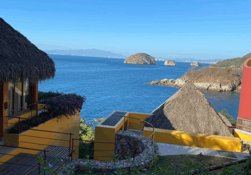 Coastal view with huts and rocky islands.