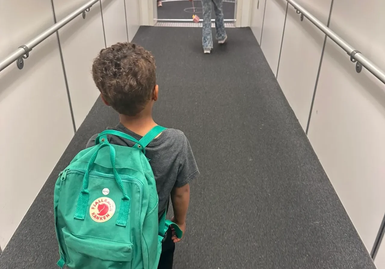 Children walking down an airplane jet bridge.