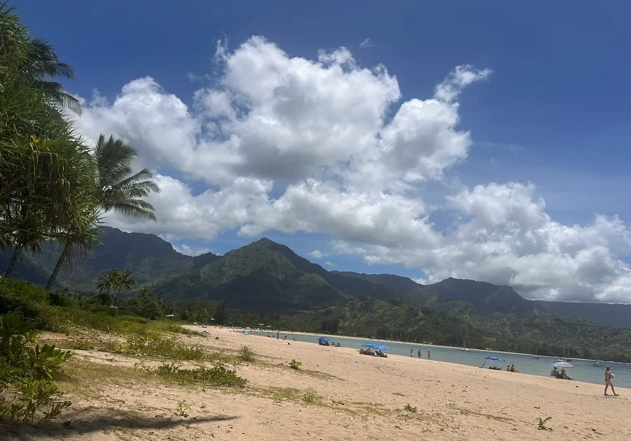 Tropical beach with mountains and cloudy sky.